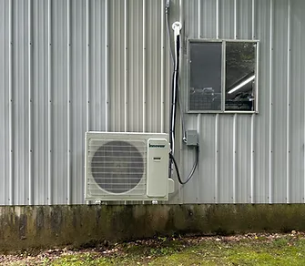 Mini-split outdoor unit mounted on the corrugated metal wall of a shop building