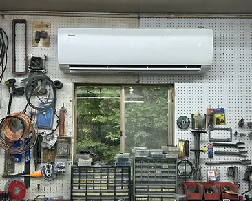 Ductless mini-split indoor unit mounted high on the pegboard wall of an organized workshop